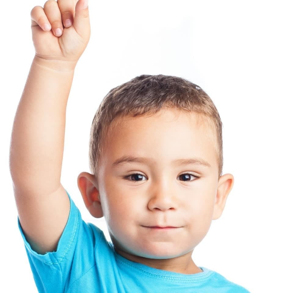 Niño levanta la mano con entusiasmo en clase